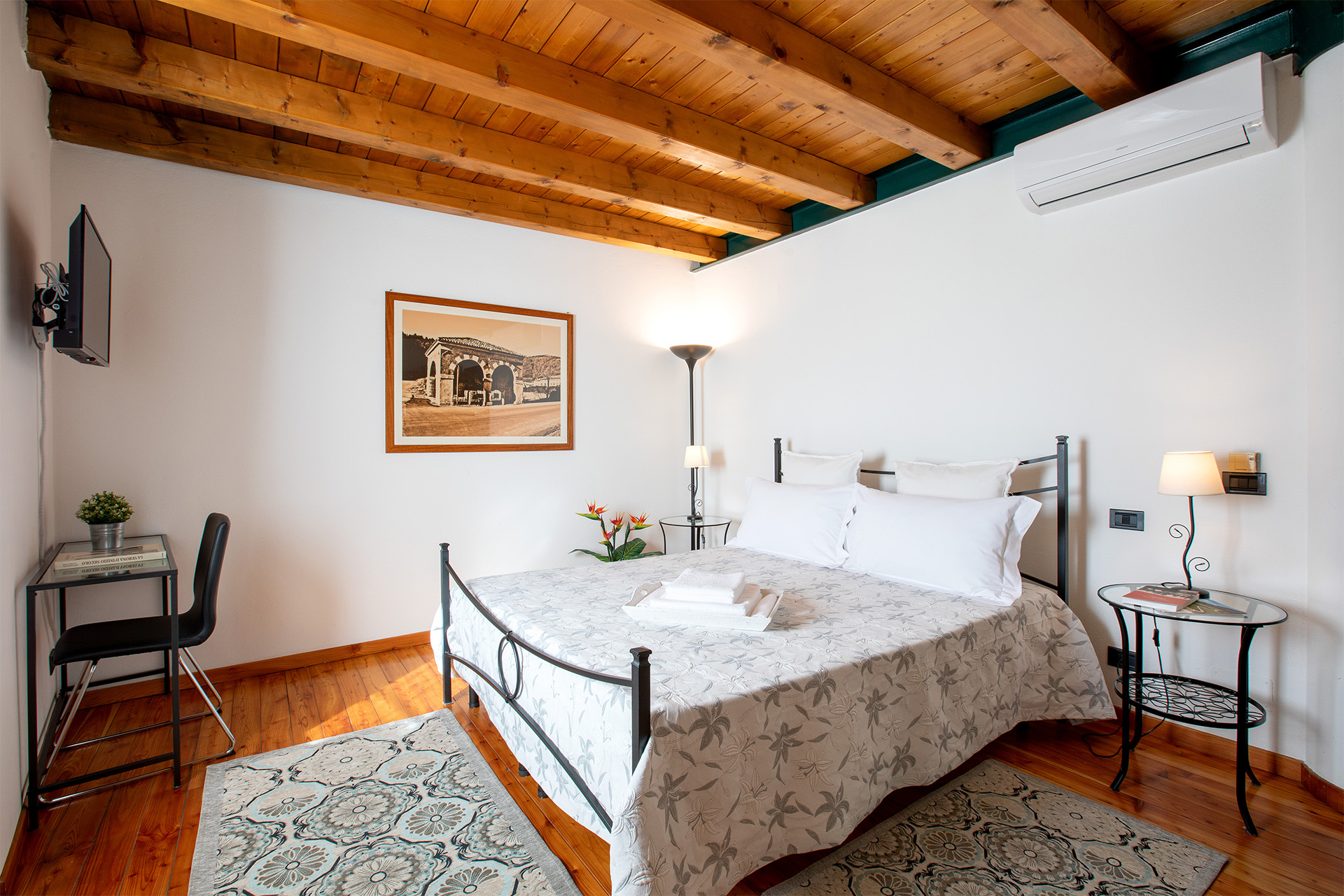 Camera La Torretta - vista laterale letto matrimoniale con soffitto legno