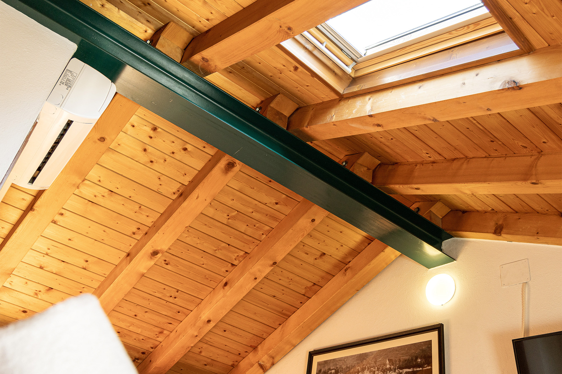 Camera Il Ponte - sottotetto in legno con trave in ferro e finestra a soffitto