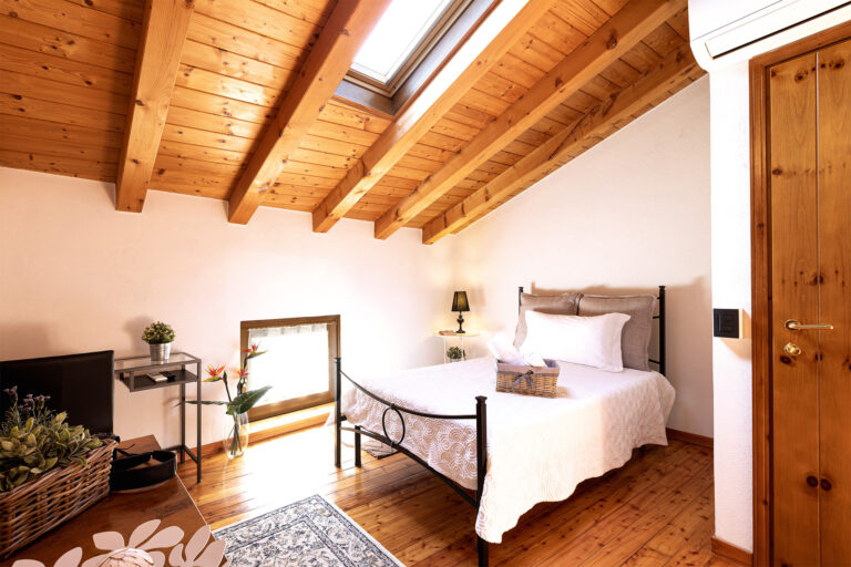 Camera Il Ponte - vista panoramica delal camera con ingresso, letto, finestra e soffitto in legno